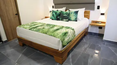 a bedroom with a large bed with green pillows at GIO Green Hotel Girardota Medellin in Girardota