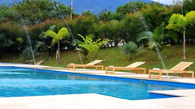 a swimming pool with two chairs and a fountain at GIO Green Hotel Girardota Medellin in Girardota