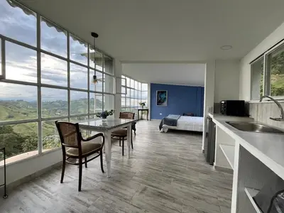 a kitchen with a table and chairs and a bedroom at Entre Nubes y Eucaliptos in Villamaría