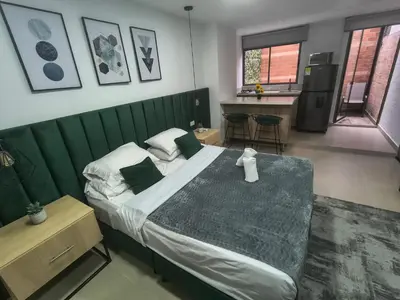 a bedroom with a large bed with a green headboard at Acogedor aparta-loft con jacuzzi in Medellín