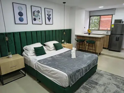 a bedroom with a large bed and a kitchen at Acogedor aparta-loft con jacuzzi in Medellín
