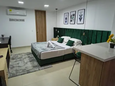 a bedroom with a bed with a green headboard at Acogedor aparta-loft con jacuzzi in Medellín