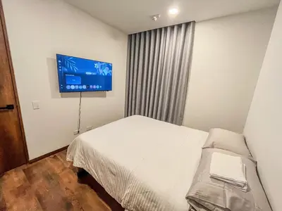 a bedroom with a bed and a flat screen tv at Modern 2BR 3Bed Country Suite | El Retiro, Ant in El Retiro