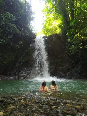 two people are swimming in a waterfall at Casa de campo Happy Hill in Cocorná