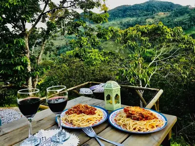 two plates of pasta on a wooden table with wine glasses at Casa de campo Happy Hill in Cocorná