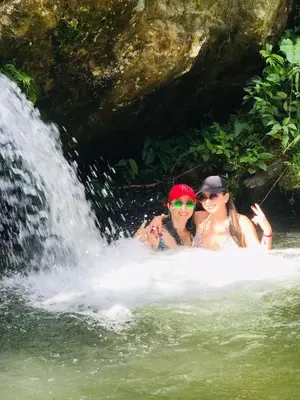 two women in the water near a waterfall at Casa de campo Happy Hill in Cocorná