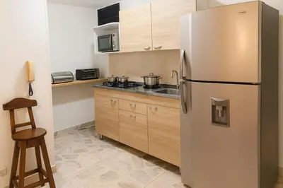 a kitchen with a stainless steel refrigerator and wooden cabinets at Oasis in Manila - El Poblado Estilo y Comfort in Medellín