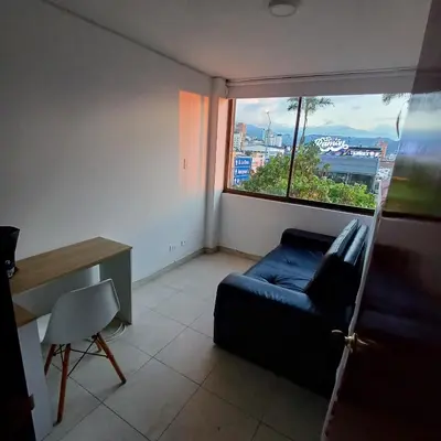 a living room with a blue couch and a window at Apartamento Con Vista Hacia La Avenida Santander Y La Ciudad in Manizales