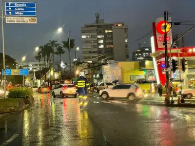 a police officer walking down a busy city street at night at Apartamento Con Vista Hacia La Avenida Santander Y La Ciudad in Manizales
