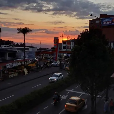 a busy city street with cars and a sunset at Apartamento Con Vista Hacia La Avenida Santander Y La Ciudad in Manizales