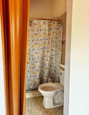 a bathroom with a toilet and a shower curtain at Ecohotel Los Cedros in Cocorná