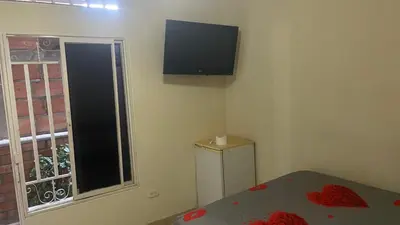 a bedroom with a bed and a television on the wall at hotel morichal in Puerto Boyacá