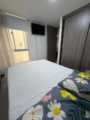 a bedroom with a bed with a flowered blanket and a television at Cómodo Apartamento - Estrato 5 in Manizales