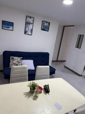 a living room with a table and a blue couch at Cómodo Apartamento - Estrato 5 in Manizales