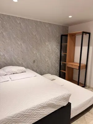 a bedroom with a white bed and a book shelf at Hostal Pacifico Encanto in Medellín