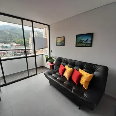 a black leather couch with colorful pillows in a living room at Acogedor Apartamento en Sabaneta in Sabaneta