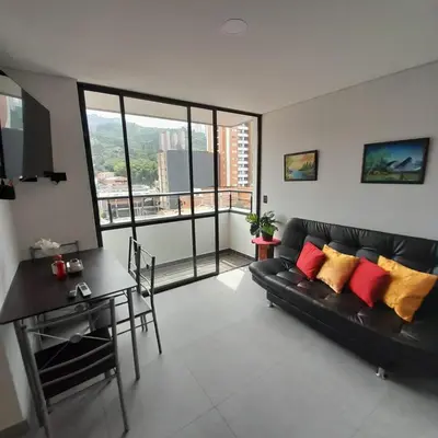 a living room with a black couch and a table at Acogedor Apartamento en Sabaneta in Sabaneta
