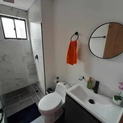 a bathroom with a toilet and a sink and a mirror at Acogedor Apartamento en Sabaneta in Sabaneta