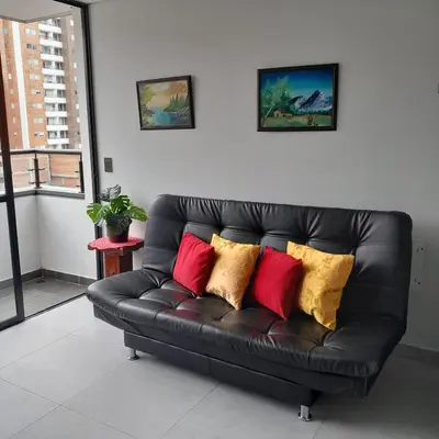 a black leather couch with colorful pillows on it at Acogedor Apartamento en Sabaneta in Sabaneta