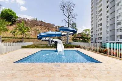 a pool with two blue umbrellas next to a building at Espectacular Apto Citadela Di Sole Santafe de Antioquia in Santa Fe de Antioquia