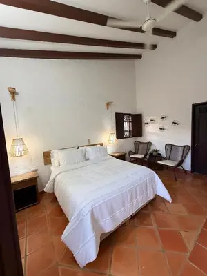 a bedroom with a large white bed and two chairs at La juana cerro tusa in Venecia