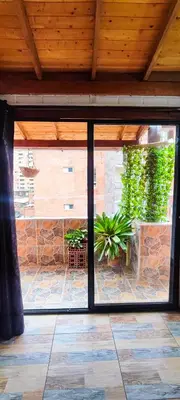an open glass door to a patio with a stone wall at Family accommodation in downtown Itagüí in Itagüí