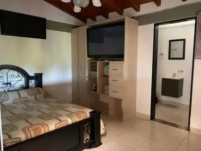 a bedroom with a bed and a flat screen tv at Finca coraline in Guarne