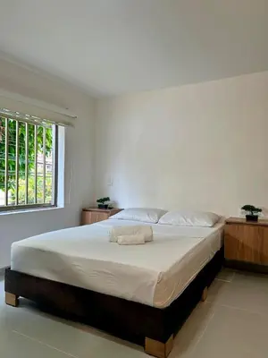 a white bedroom with a large bed with a window at Loft Laureles - Excellent location in Medellín