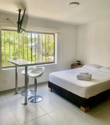 a bedroom with a bed and a desk and windows at Loft Laureles - Moderno y amplio in Medellín