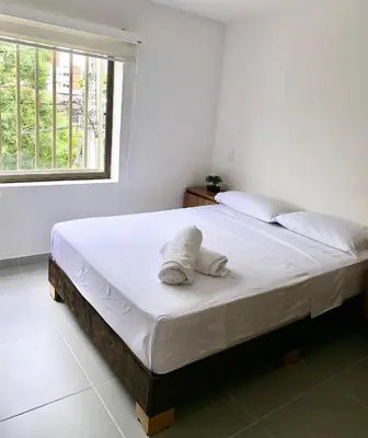 a bedroom with a bed with white sheets and a window at Loft Laureles - Moderno y amplio in Medellín
