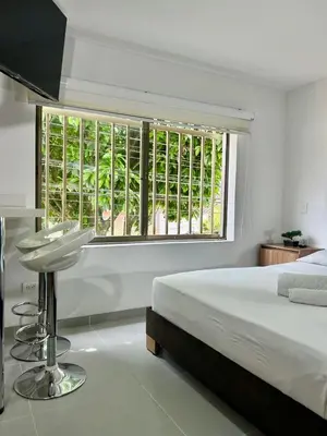 a white bedroom with a bed and a large window at Loft Laureles - Moderno y amplio in Medellín