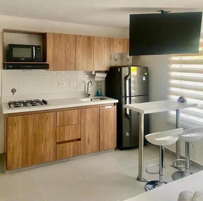 a kitchen with wooden cabinets and a sink and a refrigerator at Loft Laureles - Moderno y amplio in Medellín