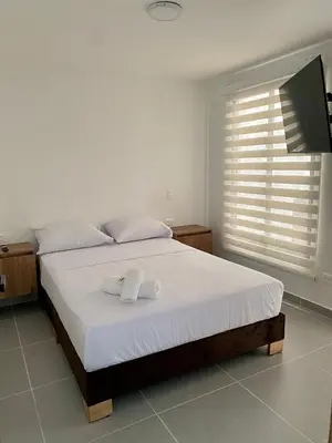 a bedroom with a bed and a flat screen tv at Loft - Laureles, interno con patio in Medellín