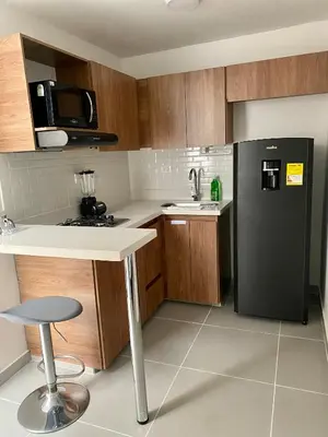 a kitchen with a black refrigerator and wooden cabinets at Loft - Laureles, interno con patio in Medellín