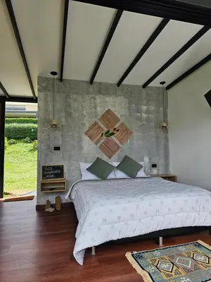 a bedroom with a large bed with a concrete wall at Equilibrium glamping in Guarne
