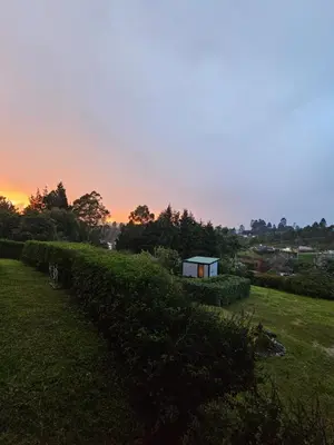 a small house on a hill with a sunset in the background at Equilibrium glamping in Guarne