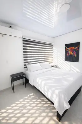 a white bedroom with a large bed and a table at KAWARA - Casa IWE in Mariquita
