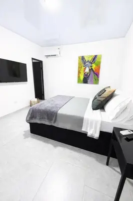 a bedroom with a bed and a painting on the wall at KAWARA - Casa IWE in Mariquita