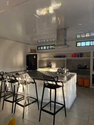 a kitchen with a counter with chairs and a kitchen island at KAWARA - Casa IWE in Mariquita