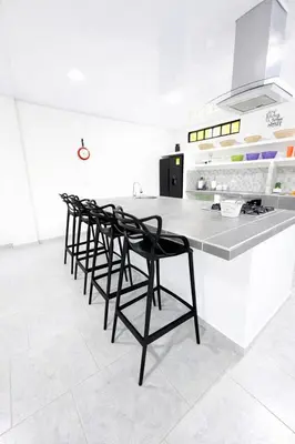 a kitchen with black chairs and a white counter at KAWARA - Casa IWE in Mariquita