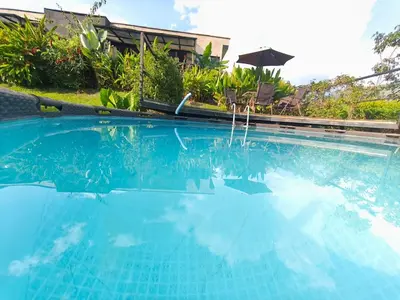 a large blue swimming pool with an umbrella at Casa Entre Montañas in Titiribí
