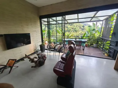 a living room with chairs and a television and a balcony at Casa Entre Montañas in Titiribí