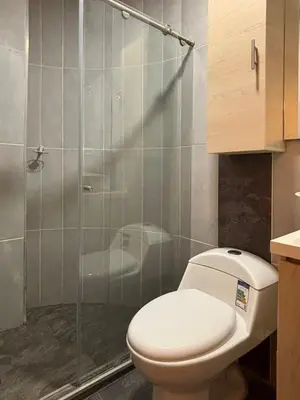 a bathroom with a toilet and a glass shower at Modern Loft Puerta de Laureles Medellin in Medellín