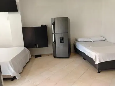 a room with two beds and a refrigerator in it at Apartaestudio Centro Histórico Medellín in Medellín