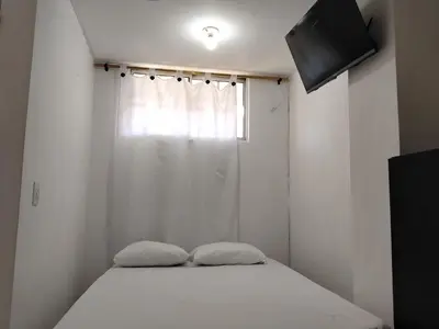 a bed with two pillows in a room with a window at Apartaestudio Centro Histórico Medellín in Medellín
