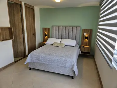 a bedroom with a large bed with two lamps at Loft urbano cerca a cable plaza in Manizales