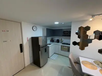 a kitchen with a stainless steel refrigerator and a table at Moderno y acogedor apartamento en sabaneta in Sabaneta