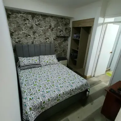 a bedroom with a bed with a stone wall at Acogedor Y Amplio Aparta estudio En El Corazón De Manizales in Manizales