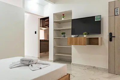 a white bedroom with a tv on a wall at Hotel Loft 72 in Medellín