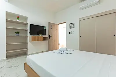 a white bedroom with a large bed and a tv at Hotel Loft 72 in Medellín